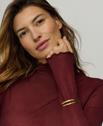 Woman wearing a maroon long-sleeve top with a plain background