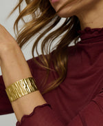 Gold bracelet on a person wearing a burgundy top