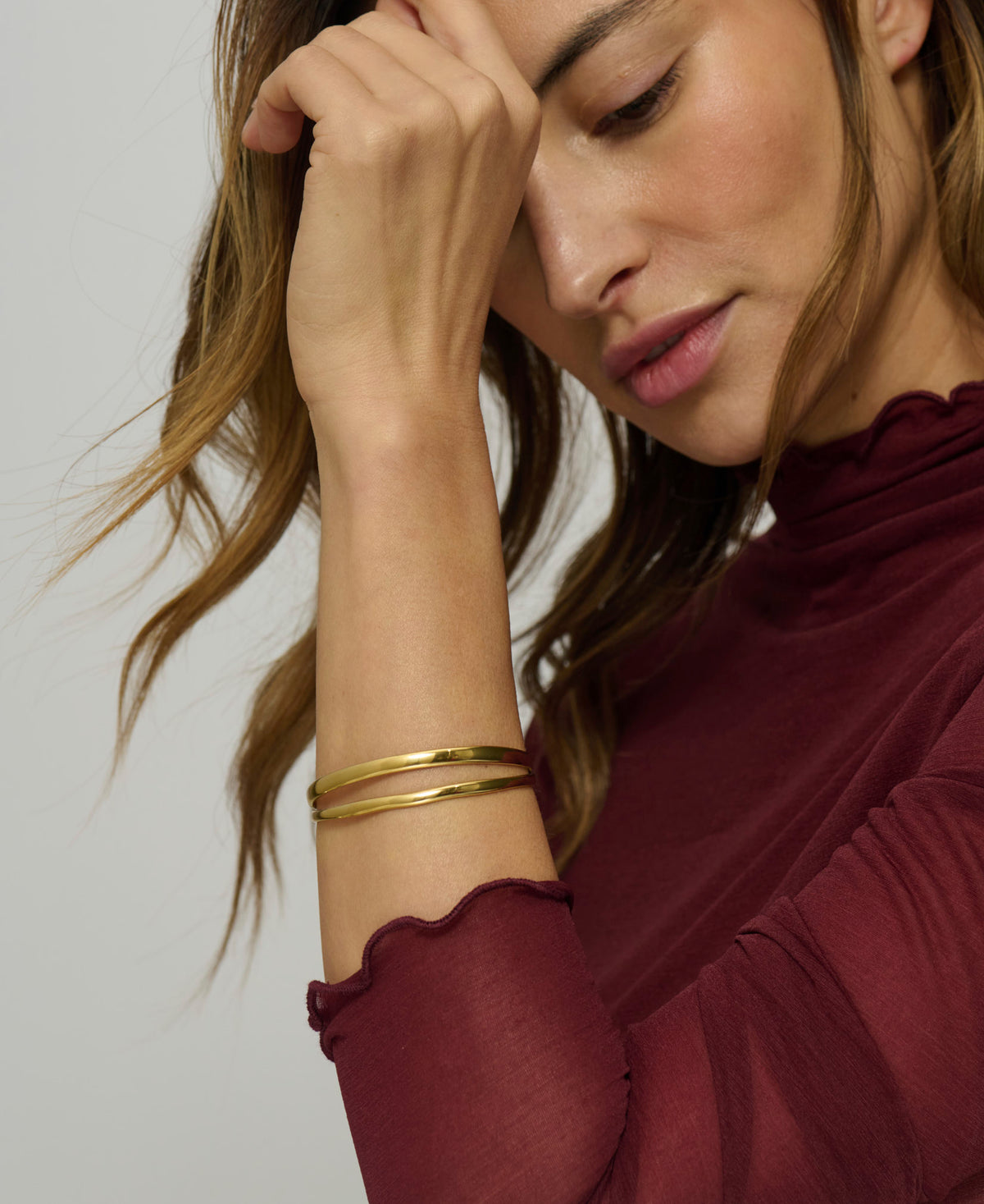 Woman wearing a gold bracelet on a plain background