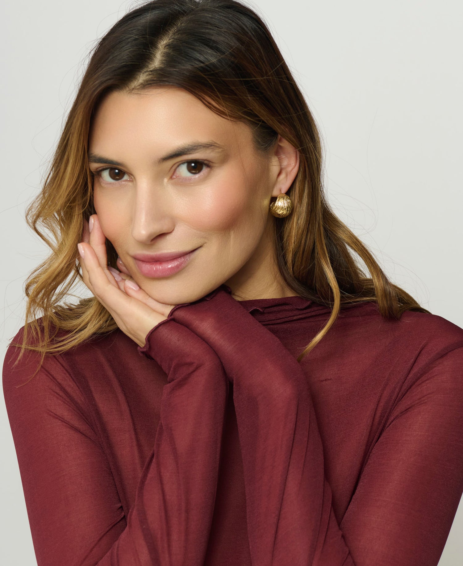 Woman wearing a burgundy top with a plain background
