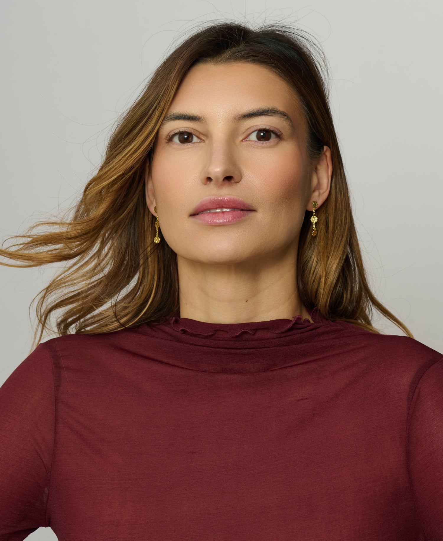Woman wearing a burgundy top against a plain background