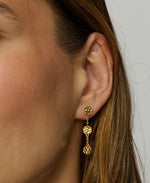 Close-up of a person wearing gold earrings with a plain background