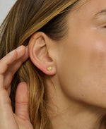 Close-up of a person wearing gold earrings with a blurred background