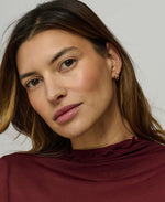 Close-up of a woman wearing a burgundy top against a neutral background