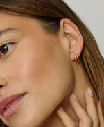 Close-up of a woman wearing a gold hoop earring.