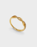 Gold ring with small zirconia on a light grey background