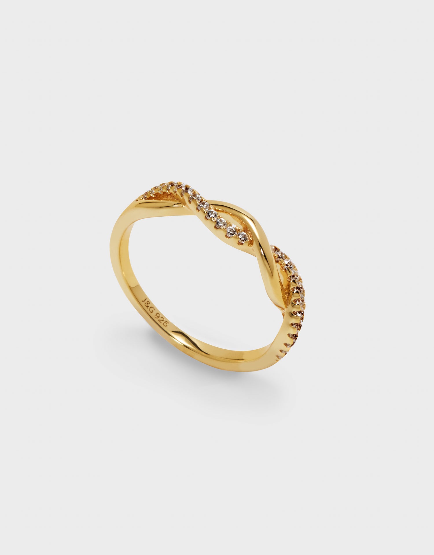 Gold ring with small zirconia on a light grey background