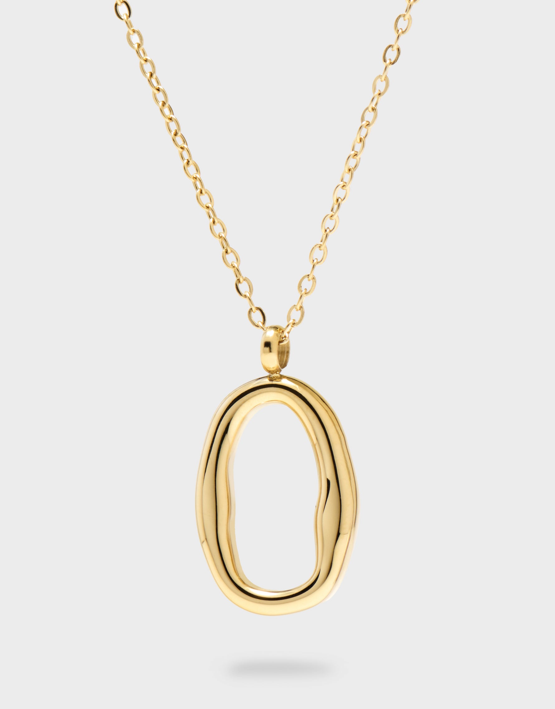 Gold necklace with an oval pendant on a light grey background
