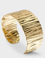 Gold cuff bracelet on a light gray background