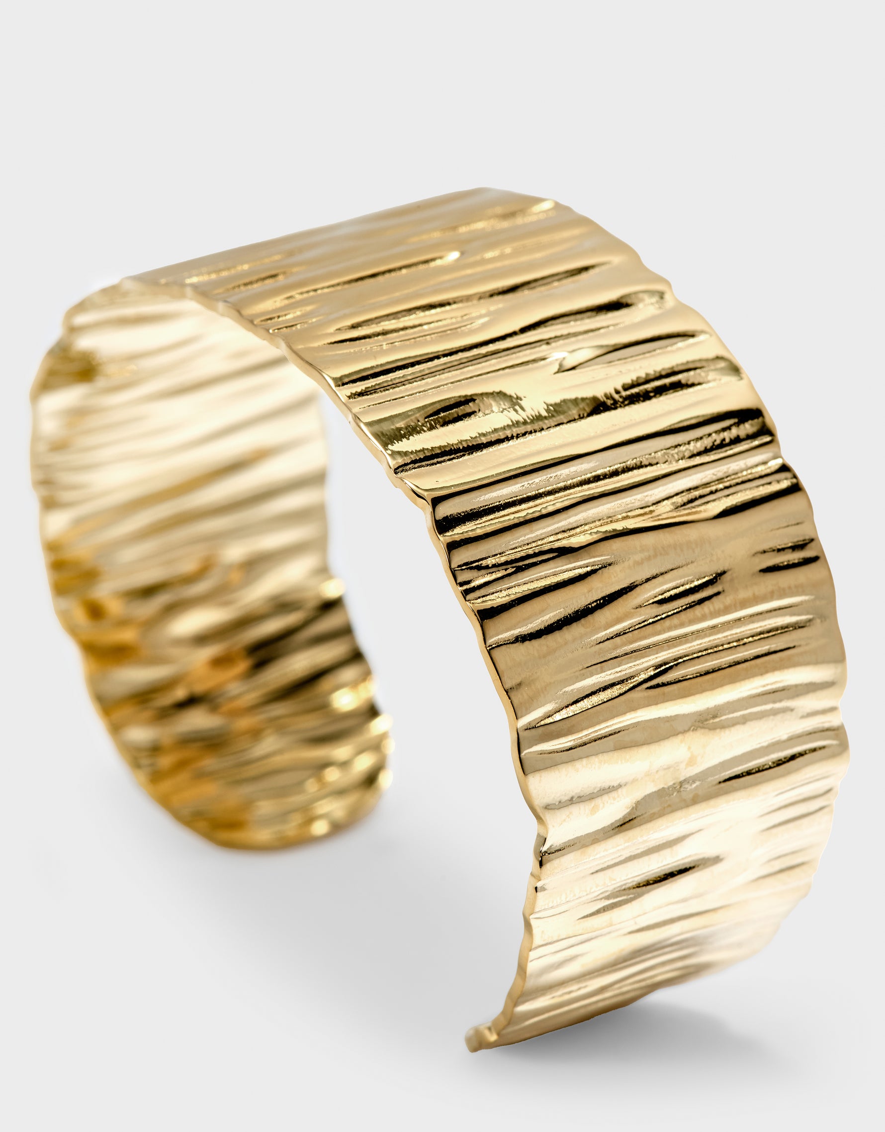 Gold cuff bracelet on a light gray background
