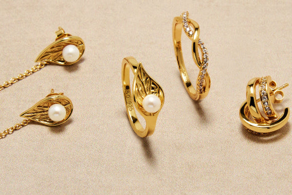 Gold jewelry set including rings and earrings on a beige background