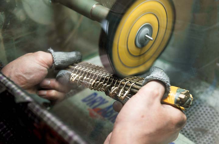 Person using a grinding wheel to sharpen a tool