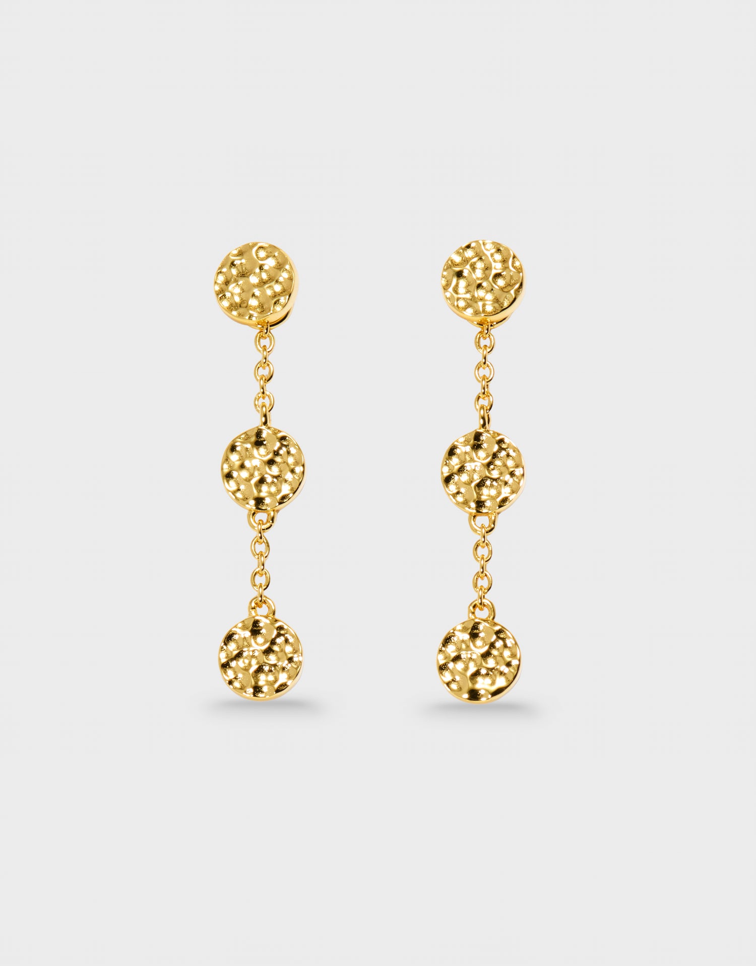 Gold earrings with spherical drops on a light gray background