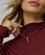 Close-up of a person wearing a gold necklace with a maroon top.