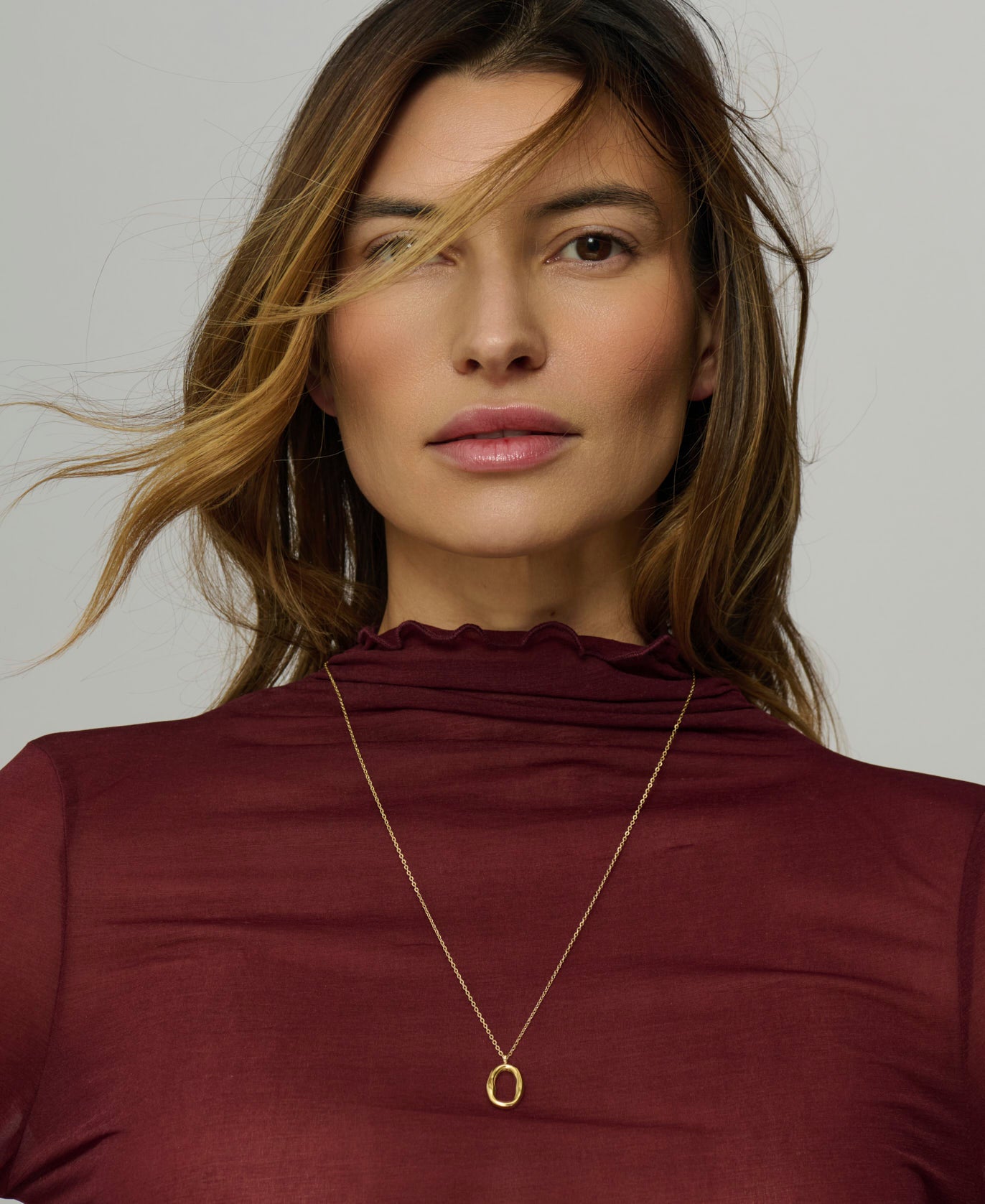 Woman wearing a gold necklace against a neutral background