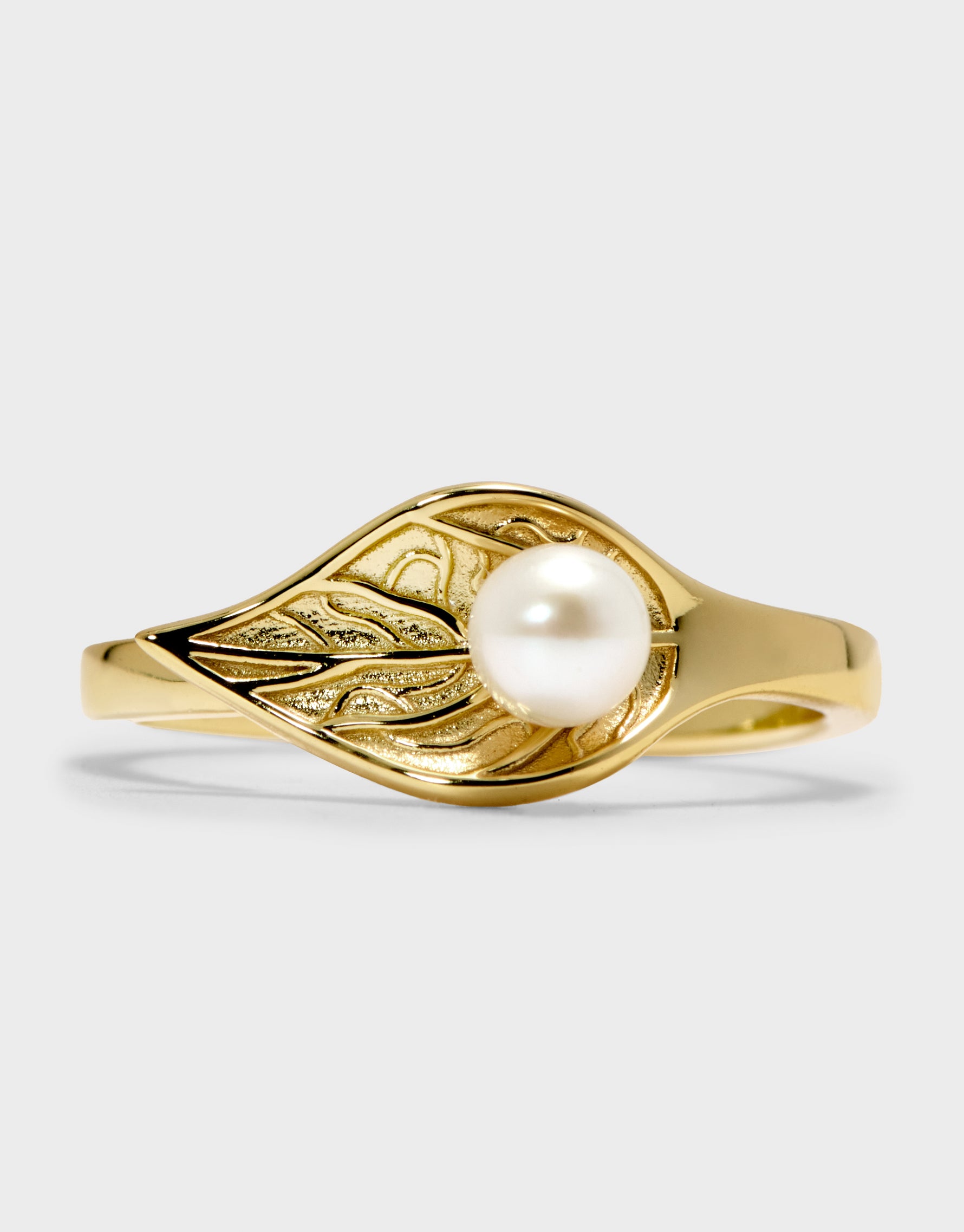 Gold ring with a pearl on a light gray background