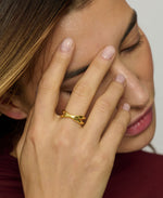 Woman wearing a gold ring on her finger with a neutral background