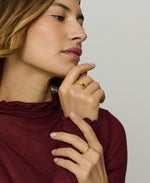 Woman wearing gold rings on a plain background
