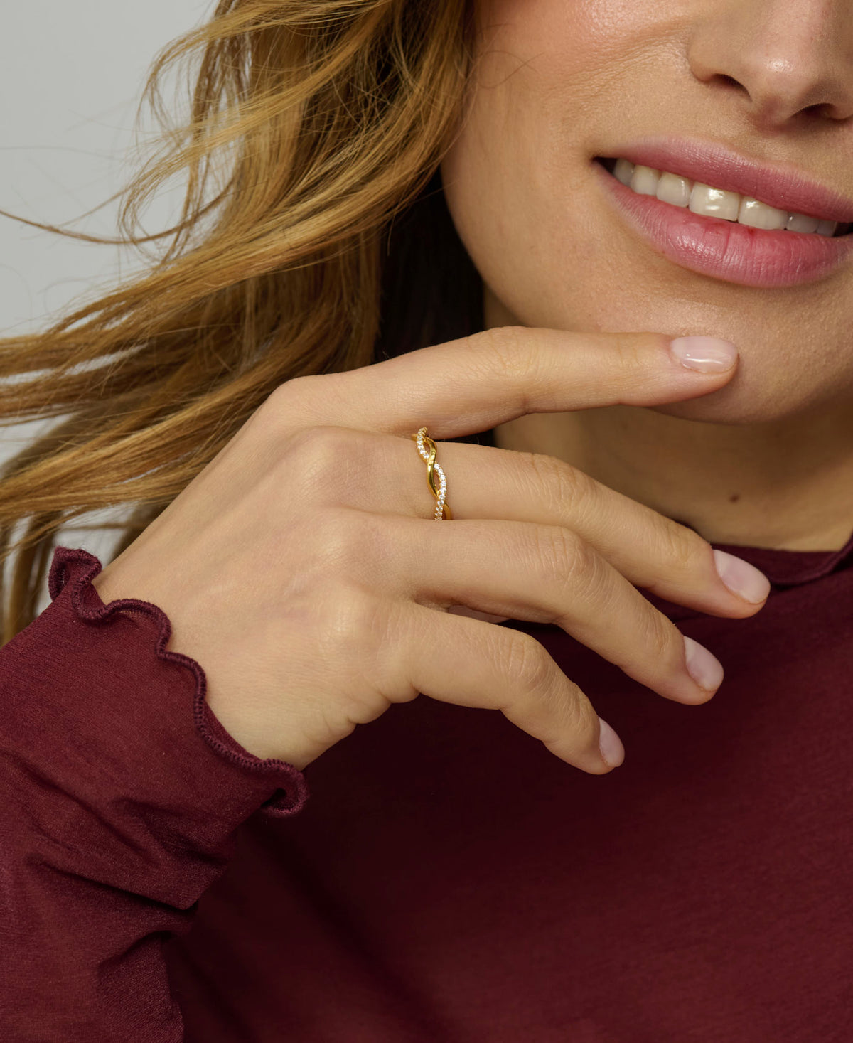 Close-up of a woman wearing a gold ring on her finger, with a blurred background.