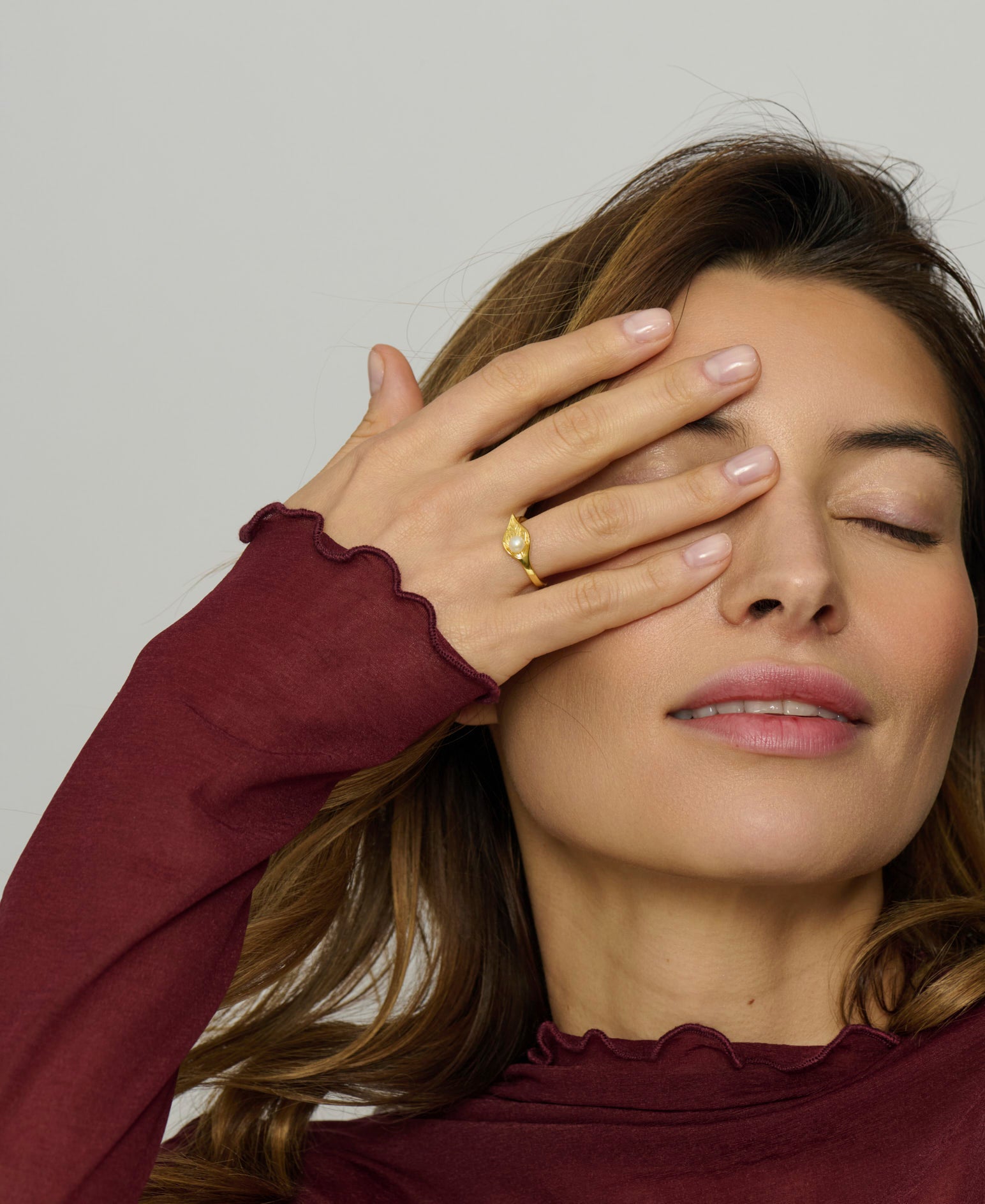 Woman wearing a burgundy long-sleeve shirt with a plain background