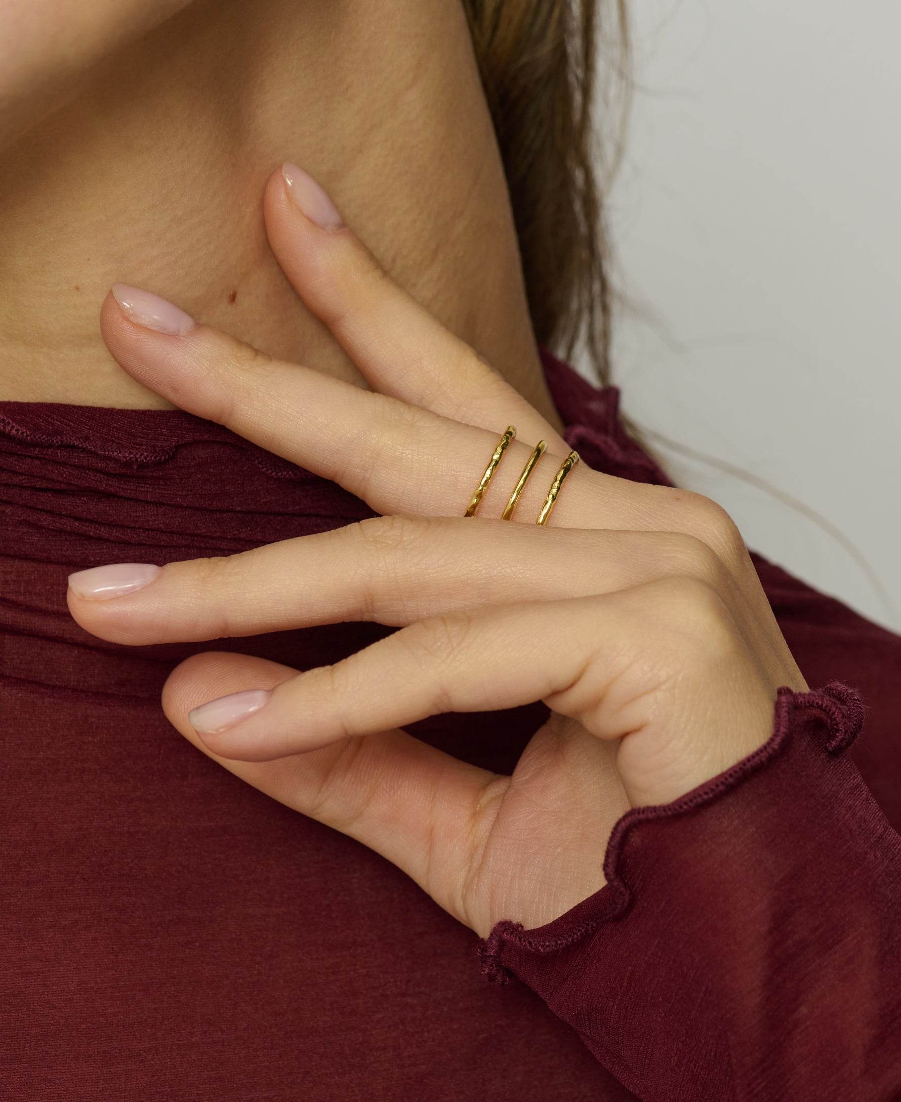 Close-up of a hand wearing gold rings with a blurred background