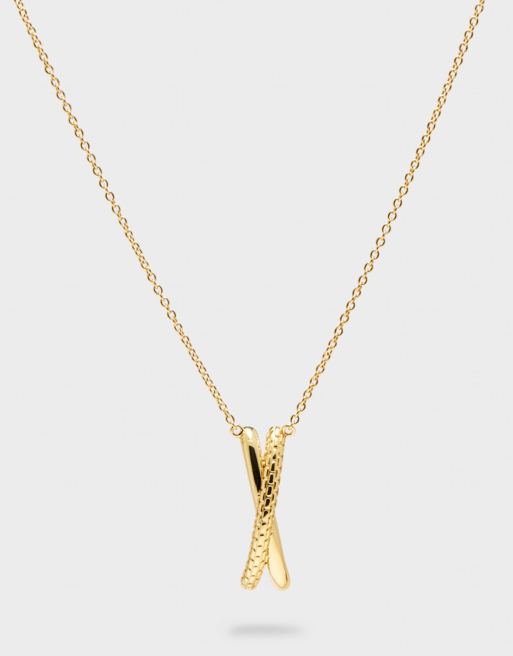 gold pendant X necklace with gold chain on grey background 