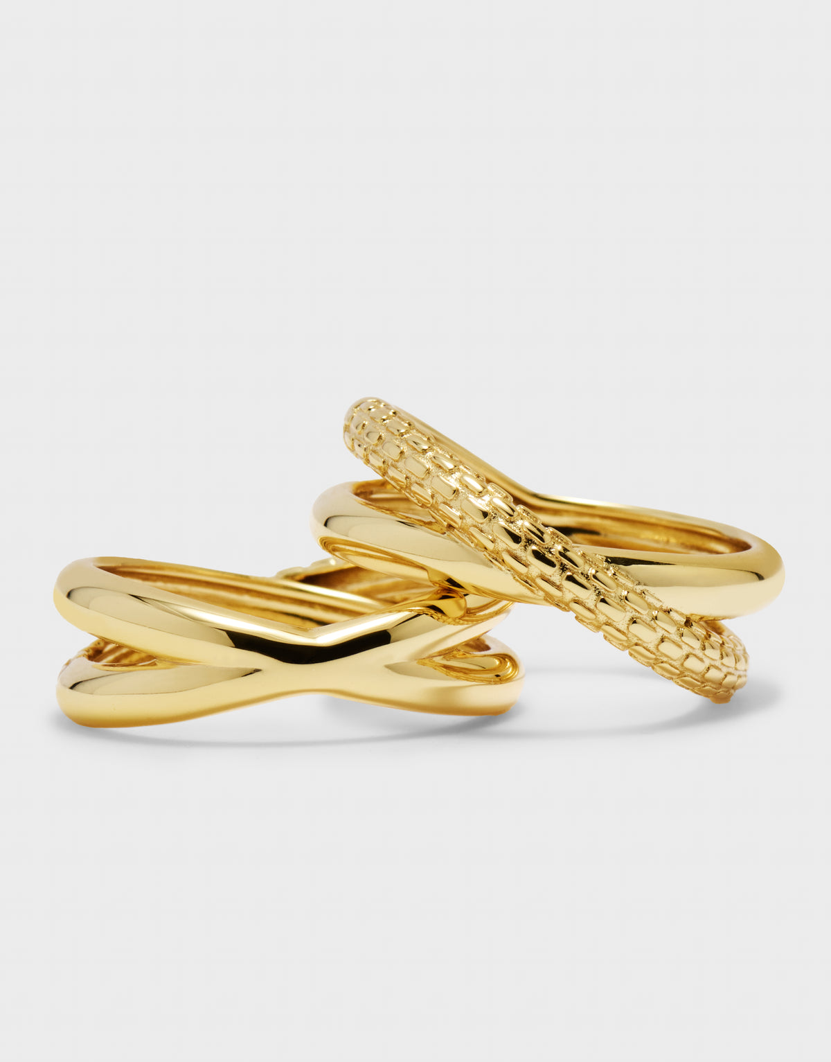 Two gold rings with different designs on a light gray background